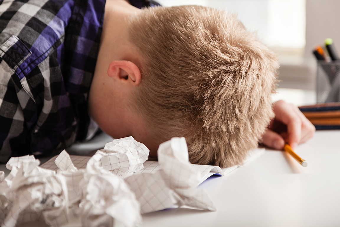 A man with his head in his hands and crumpled paper illustrating that paper prototyping is painful.